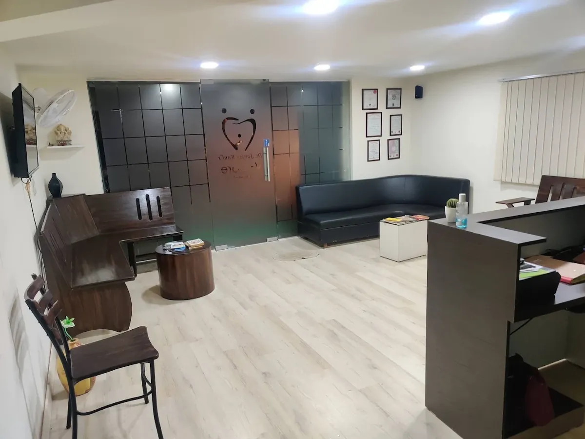 Reception and waiting area at V-Care Dental in Koramangala, with the clinic logo on the glass door